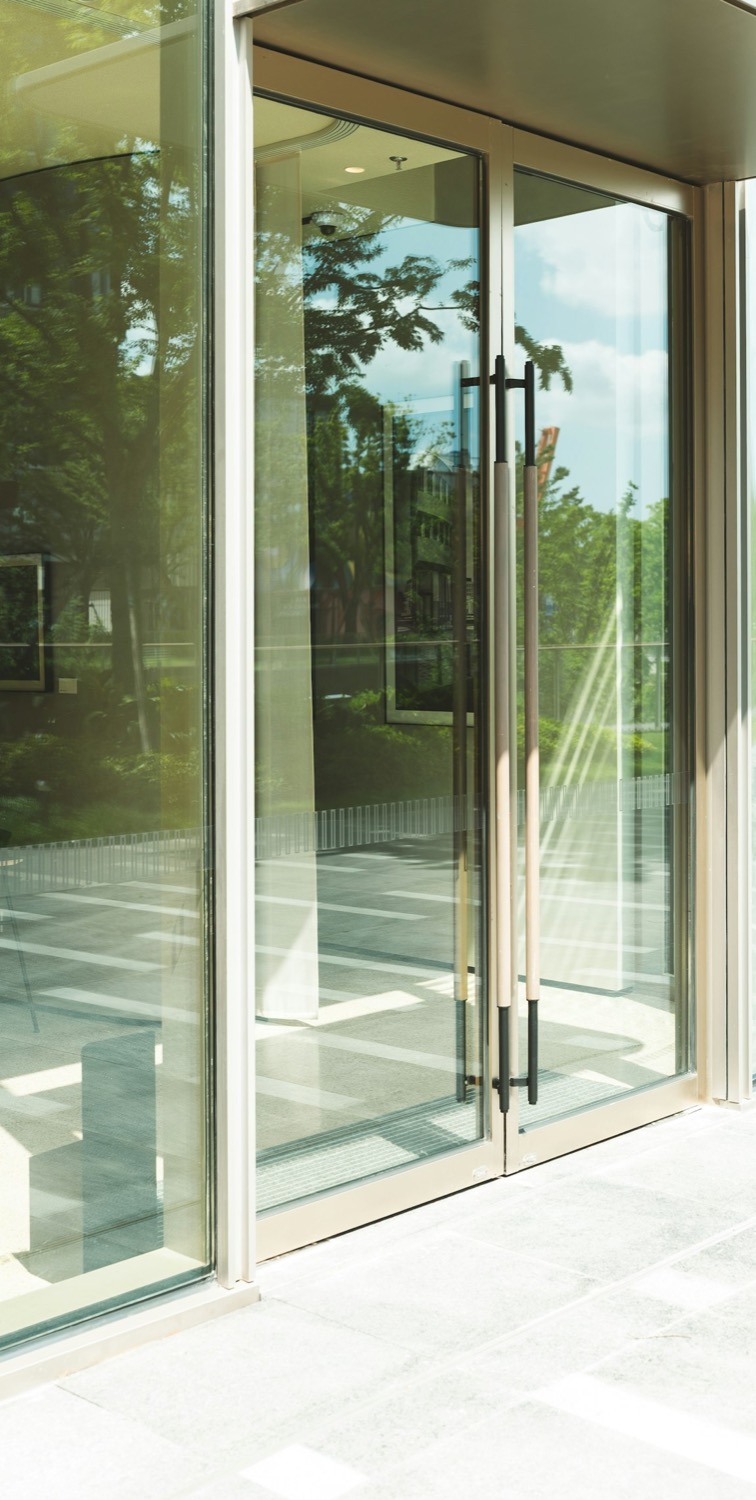 Clean glass entrance doors of a storefront reflecting trees and sky